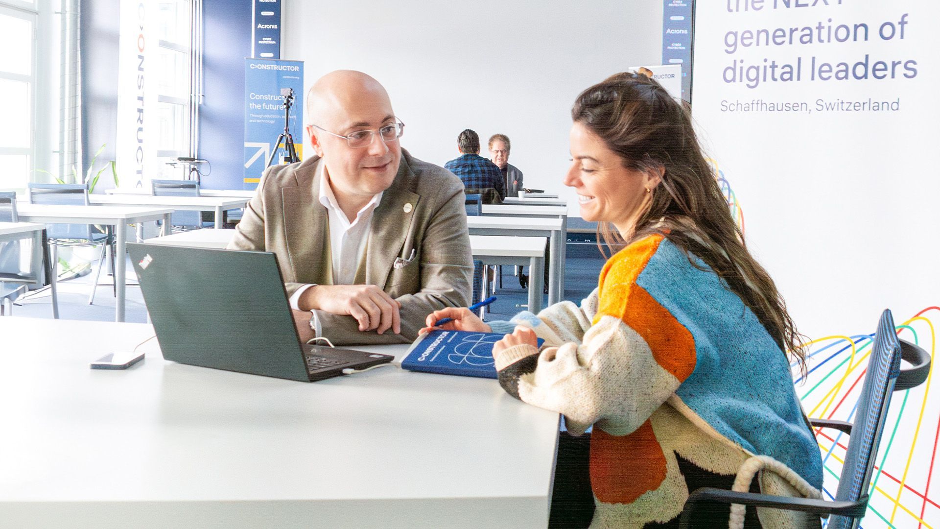 Ein Mann und eine Frau sitzen mit einem Laptop an einem Tisch.