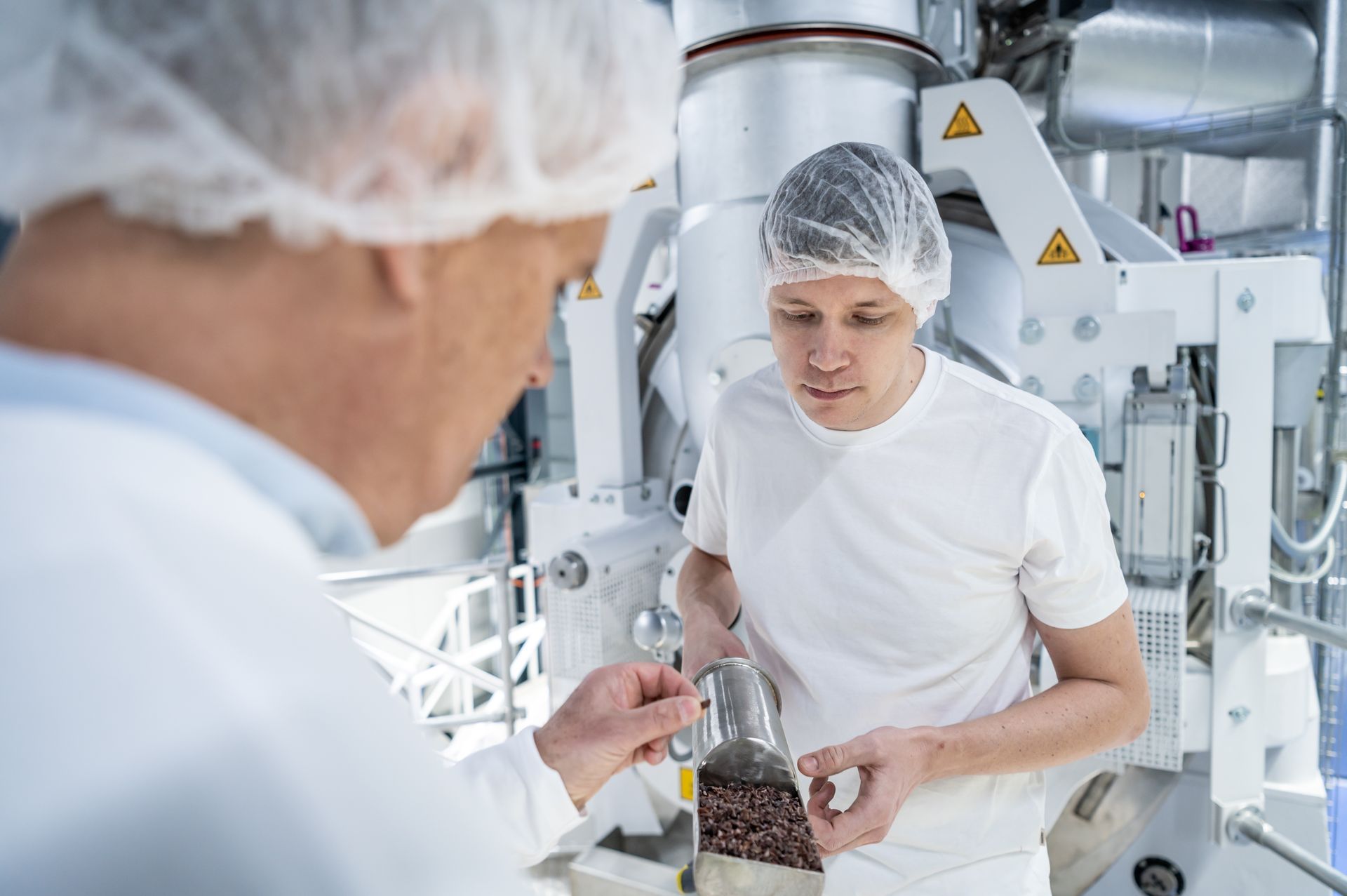 A man is standing next to another man in the Pronatec factory.