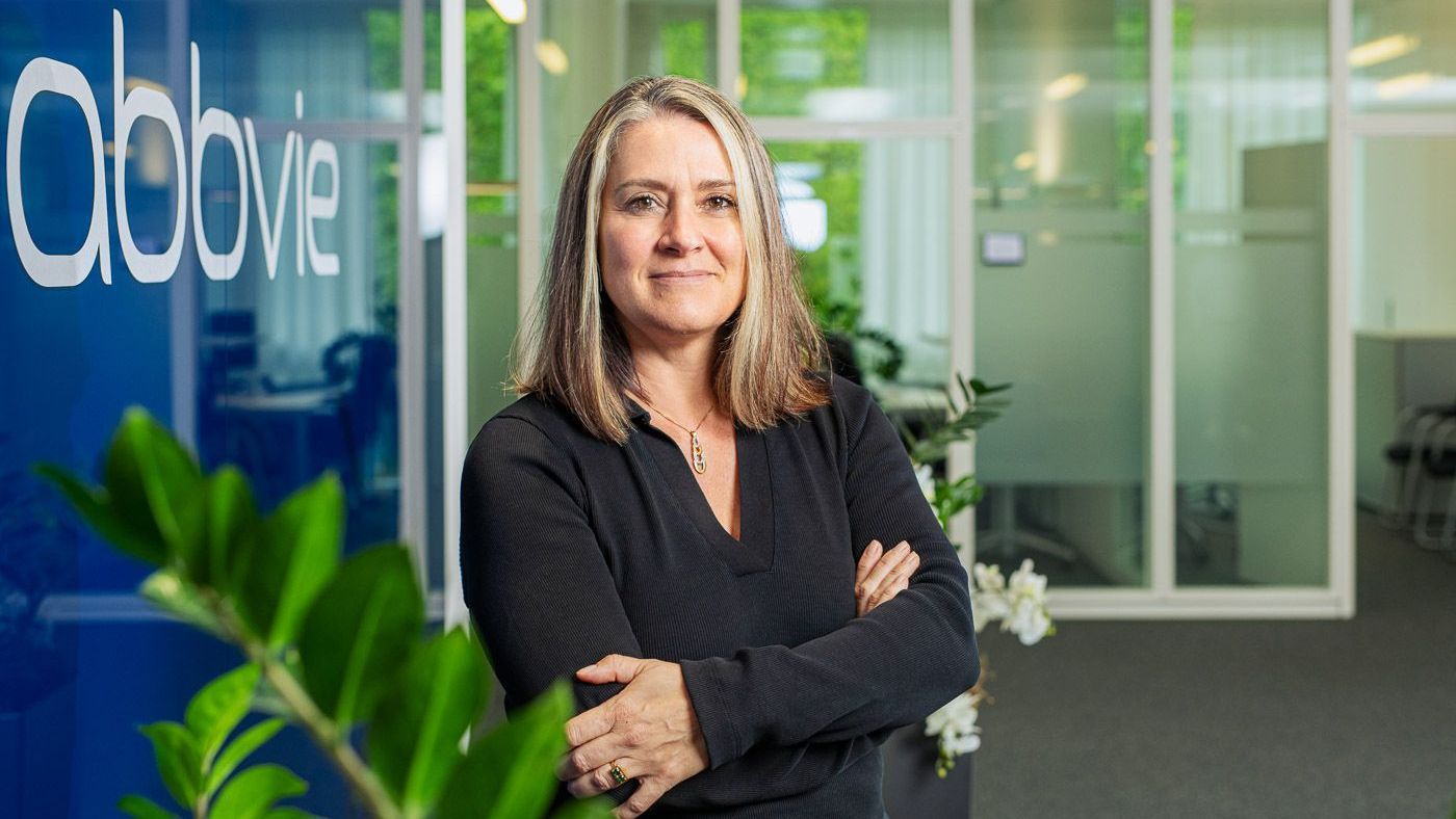 Lea Haines, Site Director & Clinical Ops Head Oncology, stands by glass door with arms crossed, confident pose.
