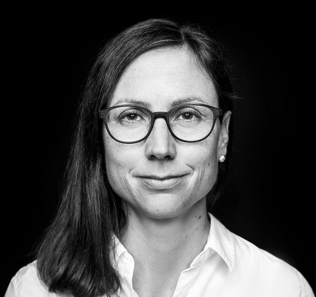 Ein Schwarzweissfoto einer Frau mit Brille und weissem Hemd.