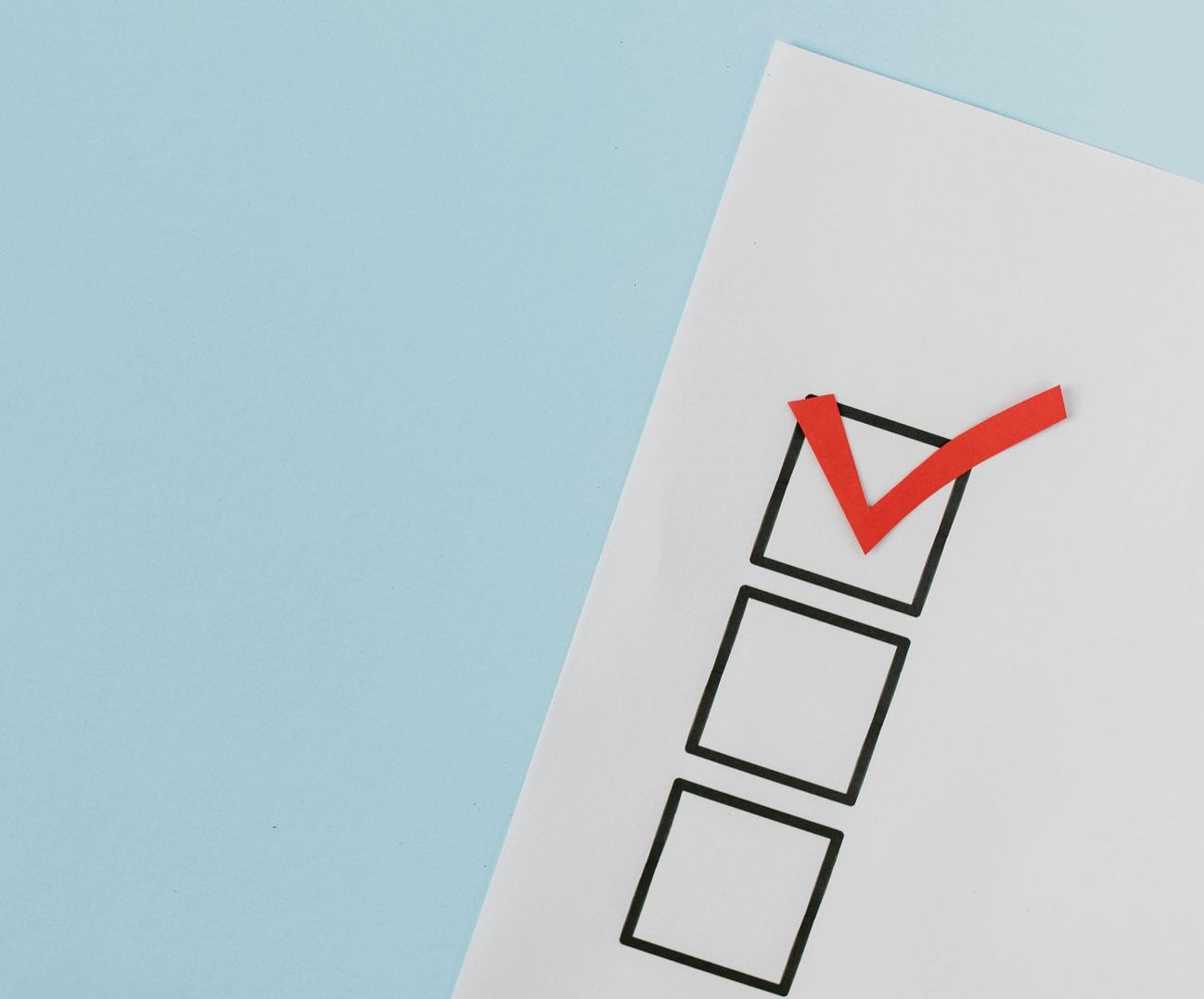 A checklist with a red check mark on it on a blue background.
