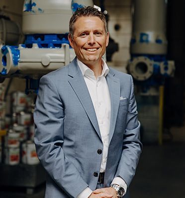 Rolf Schweizer, CEO of  Hidrostal, in a suit and white shirt is standing in front of a machine.