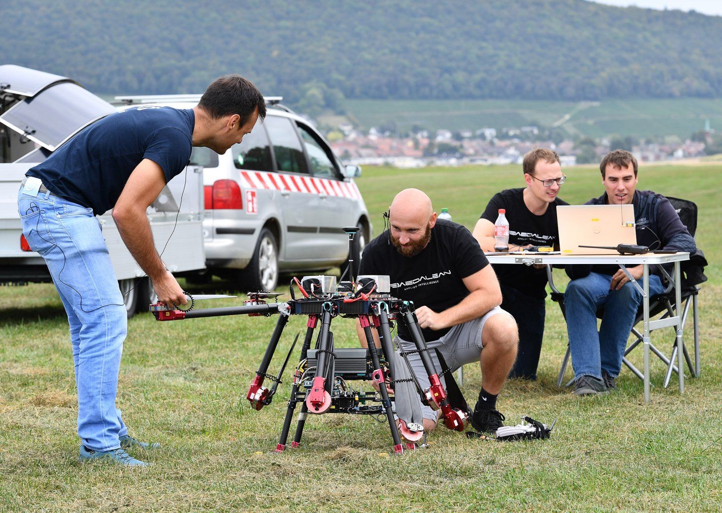 A group of men are working on a drone in a field.