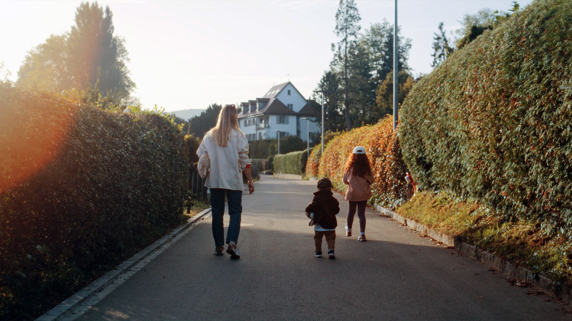 Eine Frau und zwei Kinder gehen eine Strasse entlang.