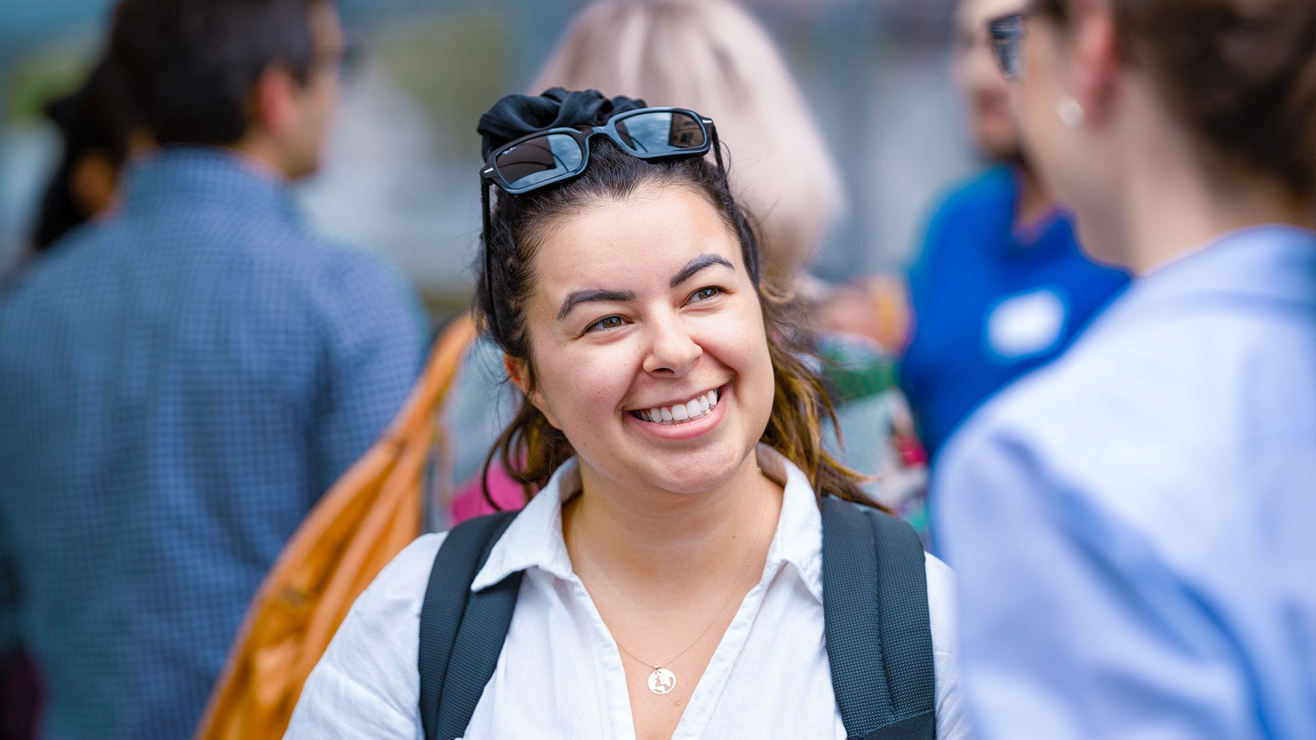 A woman is smiling while talking to another woman in a crowd of people.
