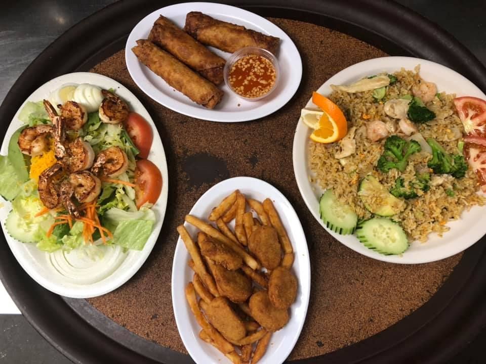 Assorted fried and fresh dishes on plates arranged on a round table with a dark tray.