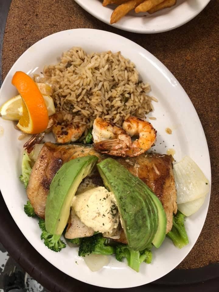 Plate with rice, grilled shrimp, avocado slices, and lemon wedges on a table