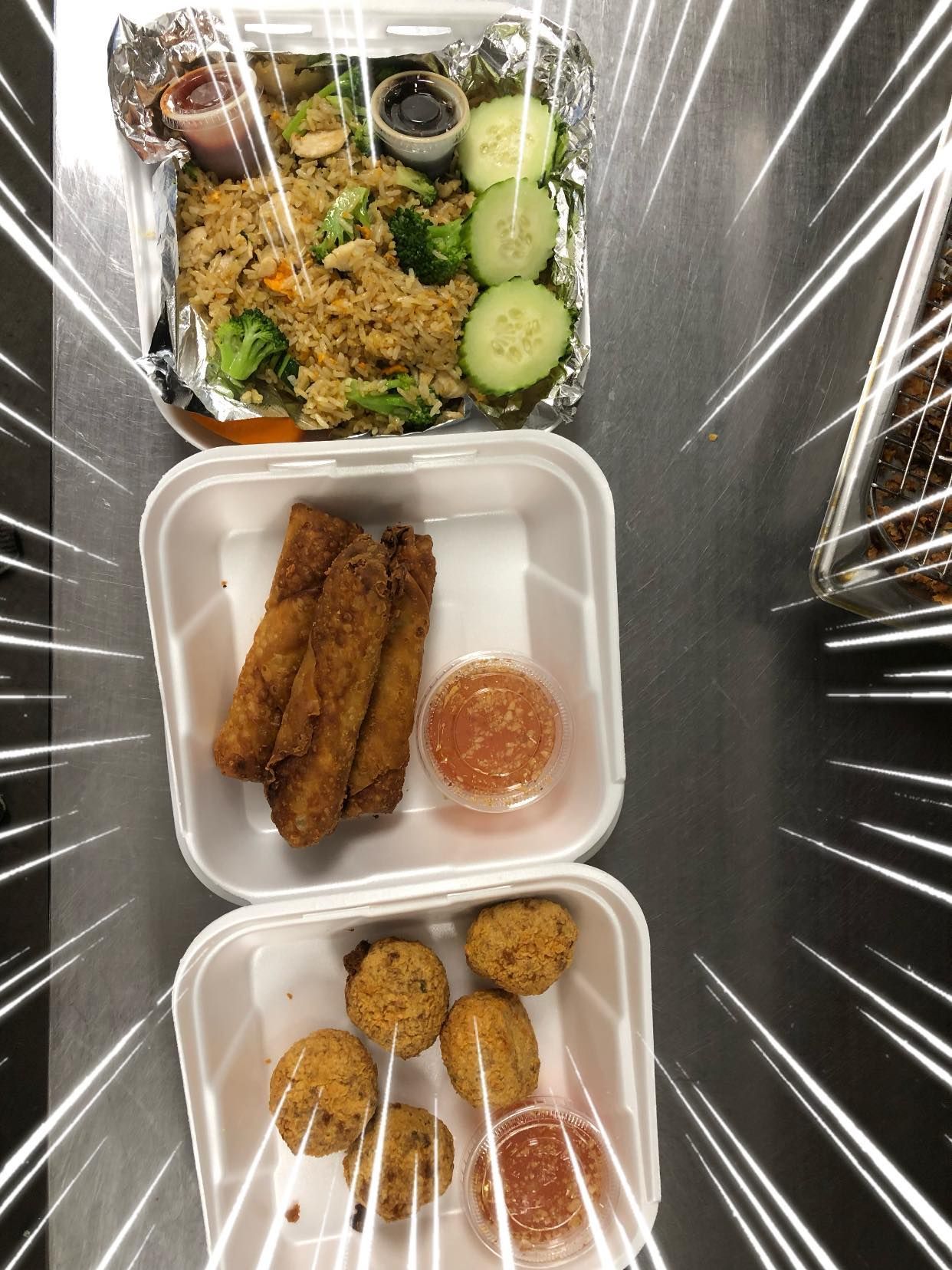 Three takeout food containers with fried snacks, rice, cucumbers, and dipping sauce on a table.