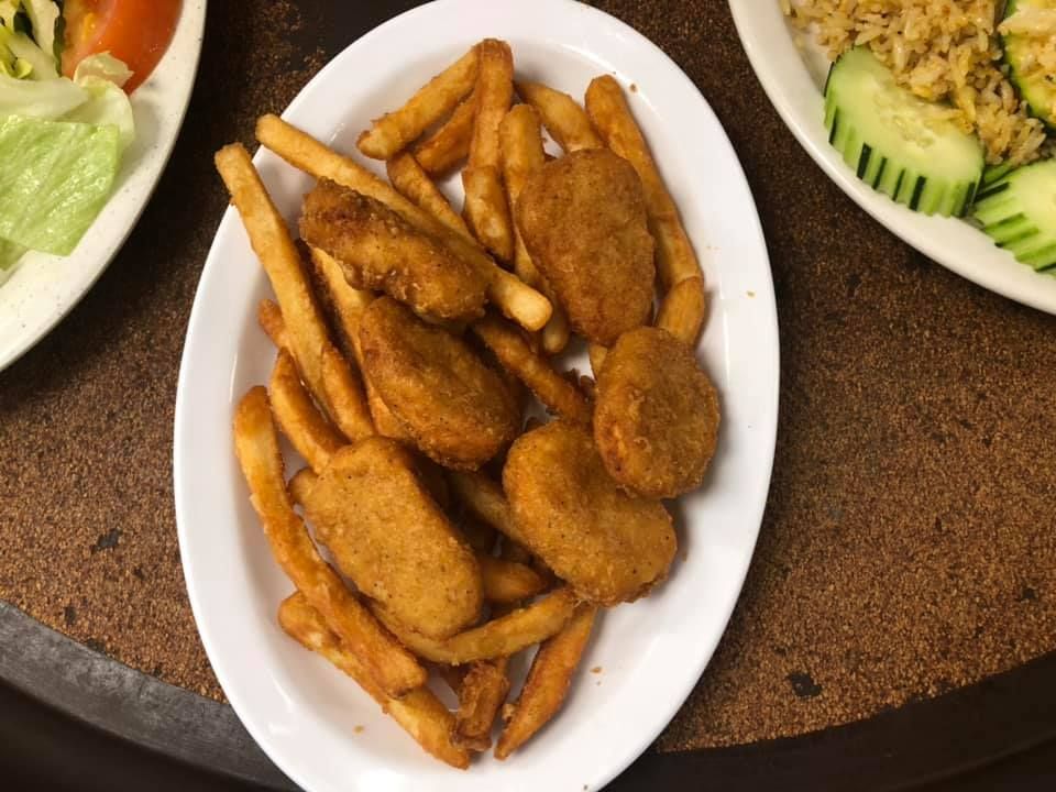Plate of golden fried snacks on a table, with salad plates partially visible around it