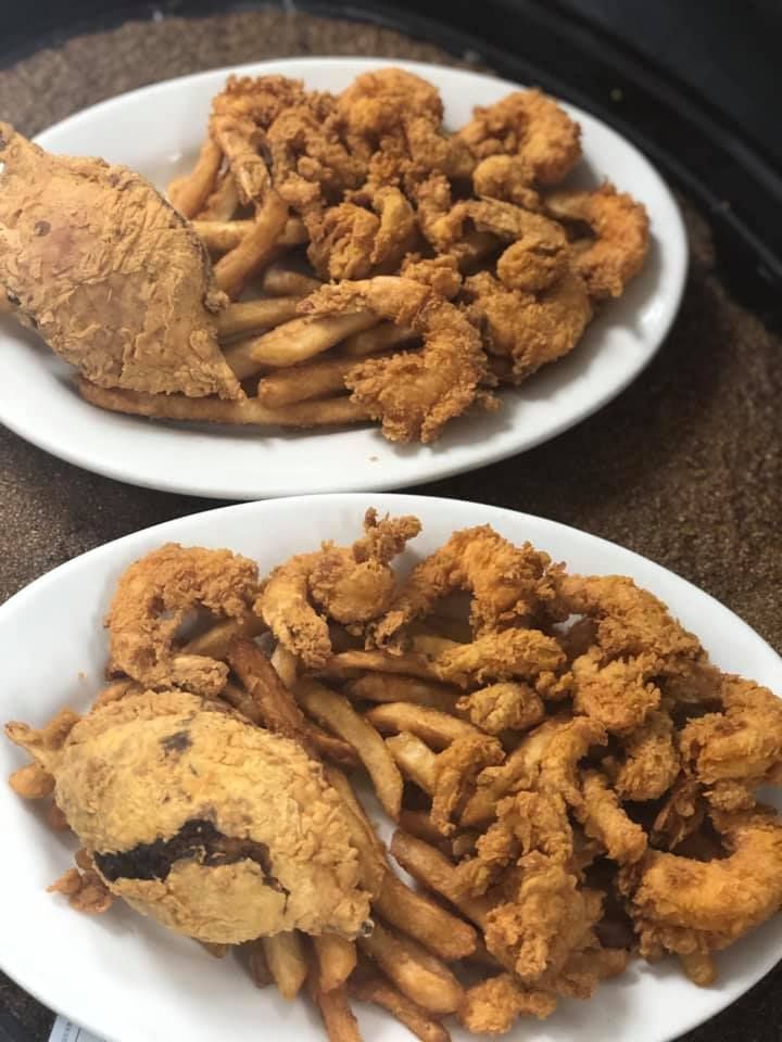 Two plates of fried chicken and seasoned fries on a table