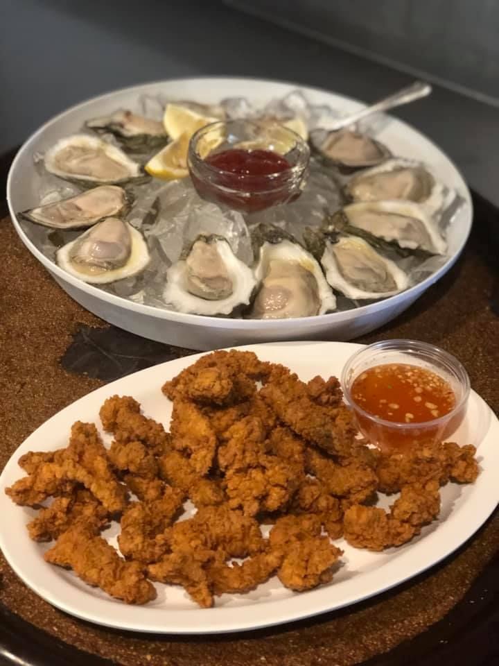 Platter of fried seafood bites and a tray of oysters on ice with dipping sauce