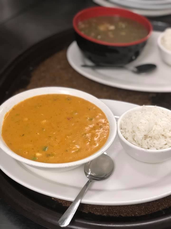 Tray with orange curry, white rice, and a bowl of soup on a table