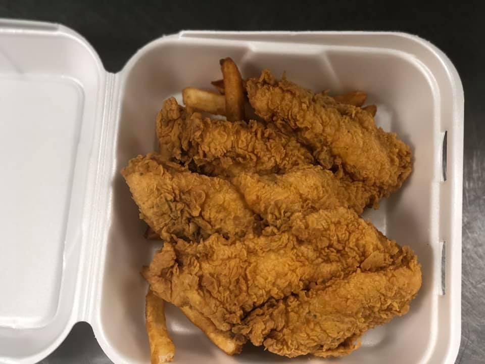 Open takeout box with three pieces of fried chicken tenders on white tray.