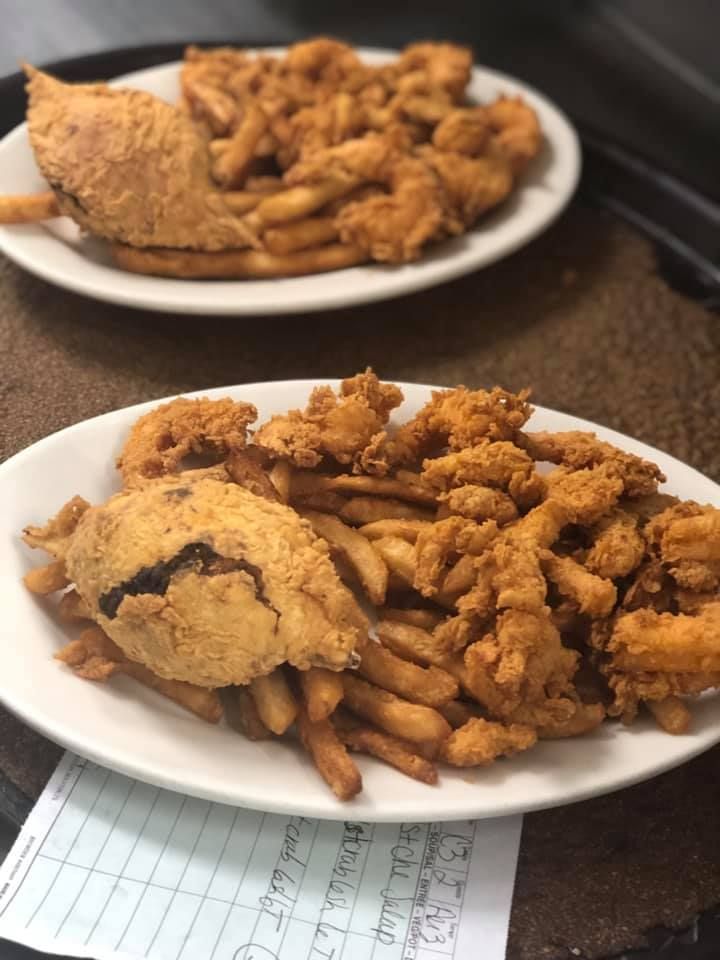 Two plates of fried food on a table, with chicken and fries on the front plate
