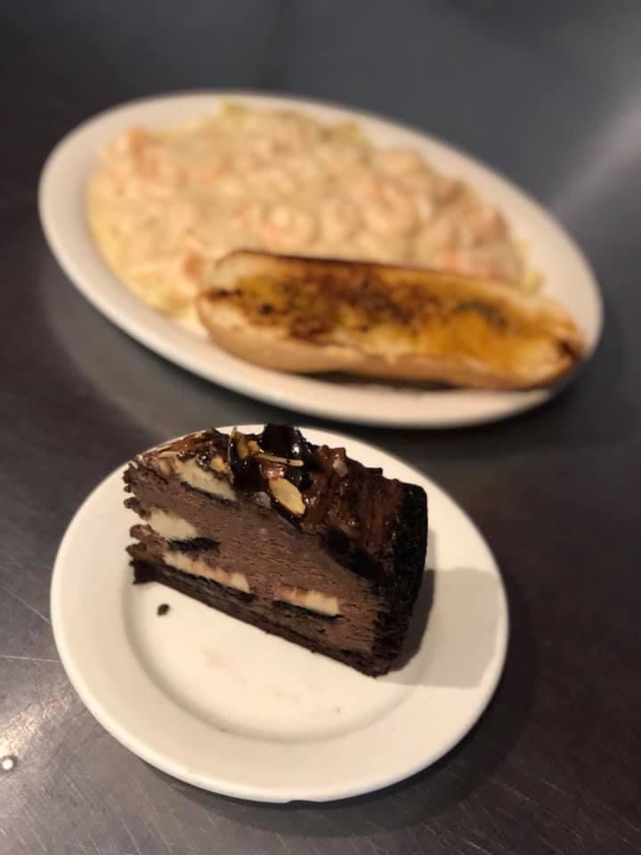 Dessert plate with a slice of chocolate cake in front and a banana on a white plate behind it
