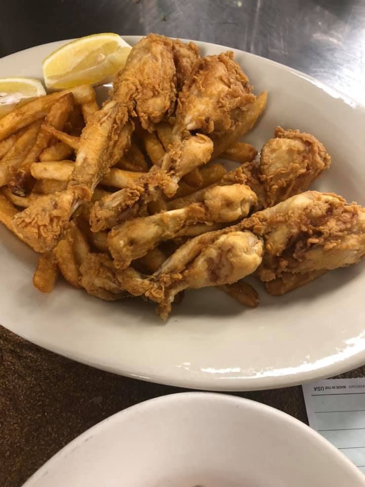 Plate of fried chicken wings and fries with lemon wedges on a table