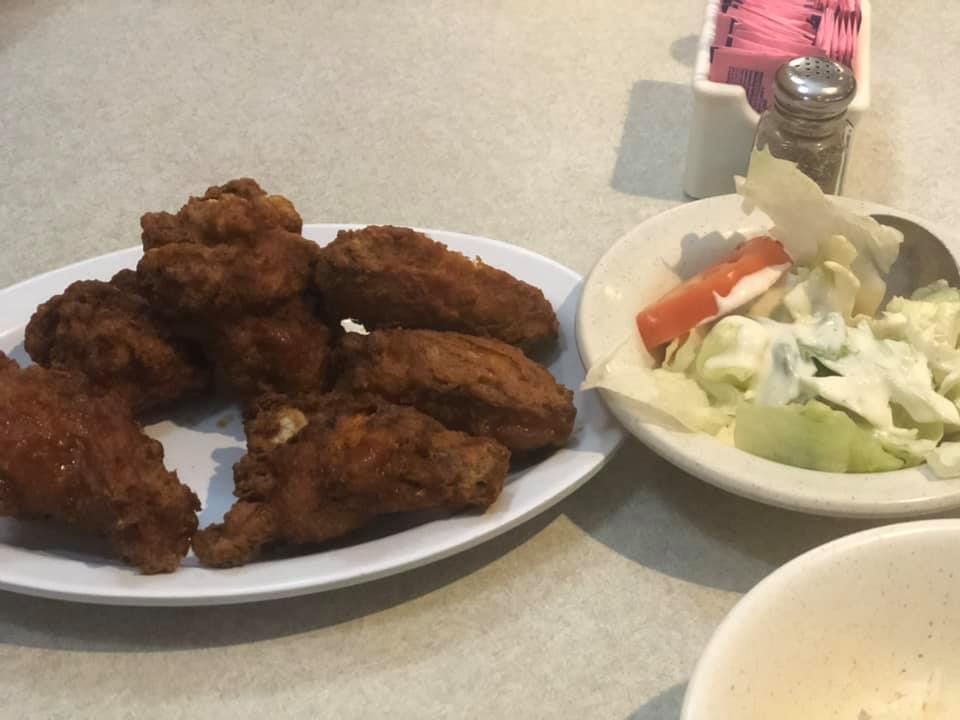 Plate of fried chicken wings beside a side salad on a table