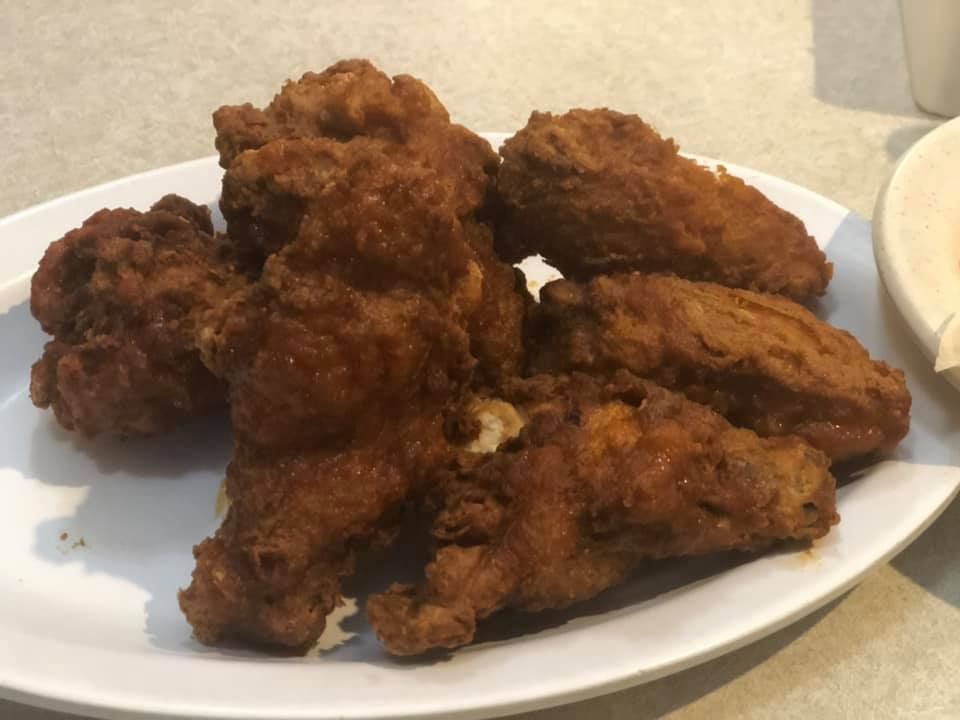 Plate of crispy fried chicken pieces on a table next to a bowl