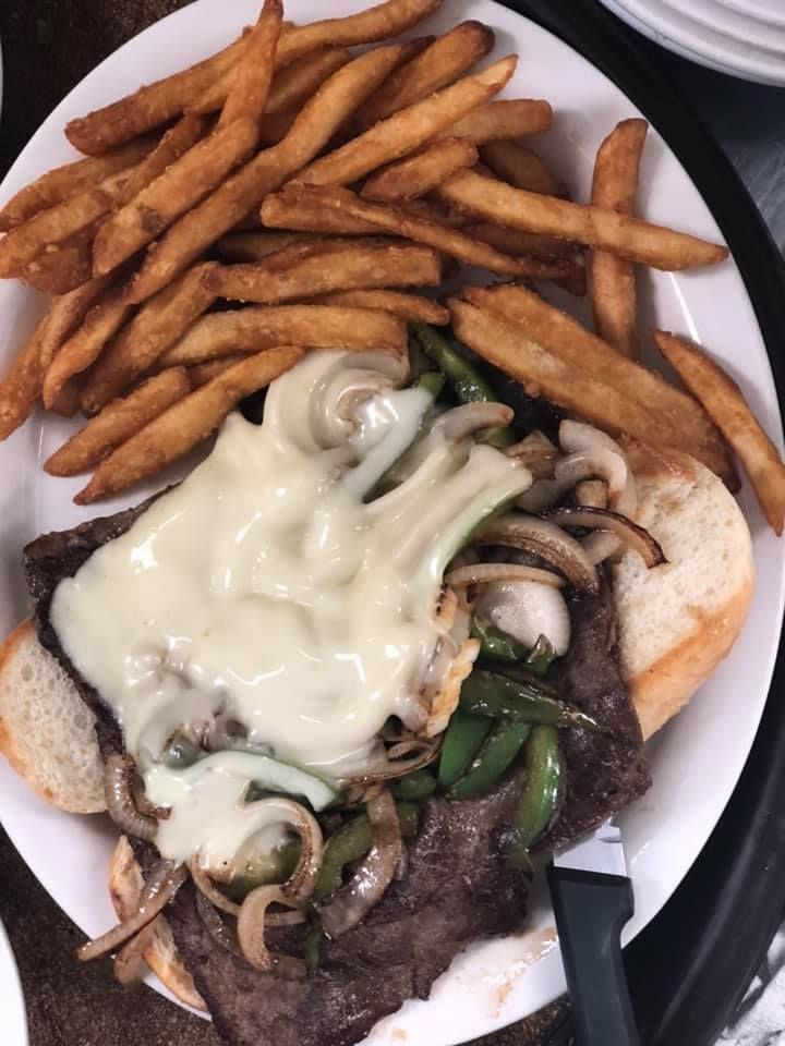 Plate of fries topped with melted cheese and onions beside grilled steak and green peppers