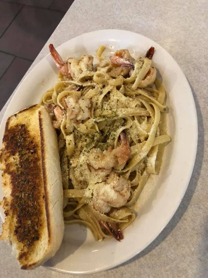 Plate of creamy pasta with shrimp and garlic bread on a white dish