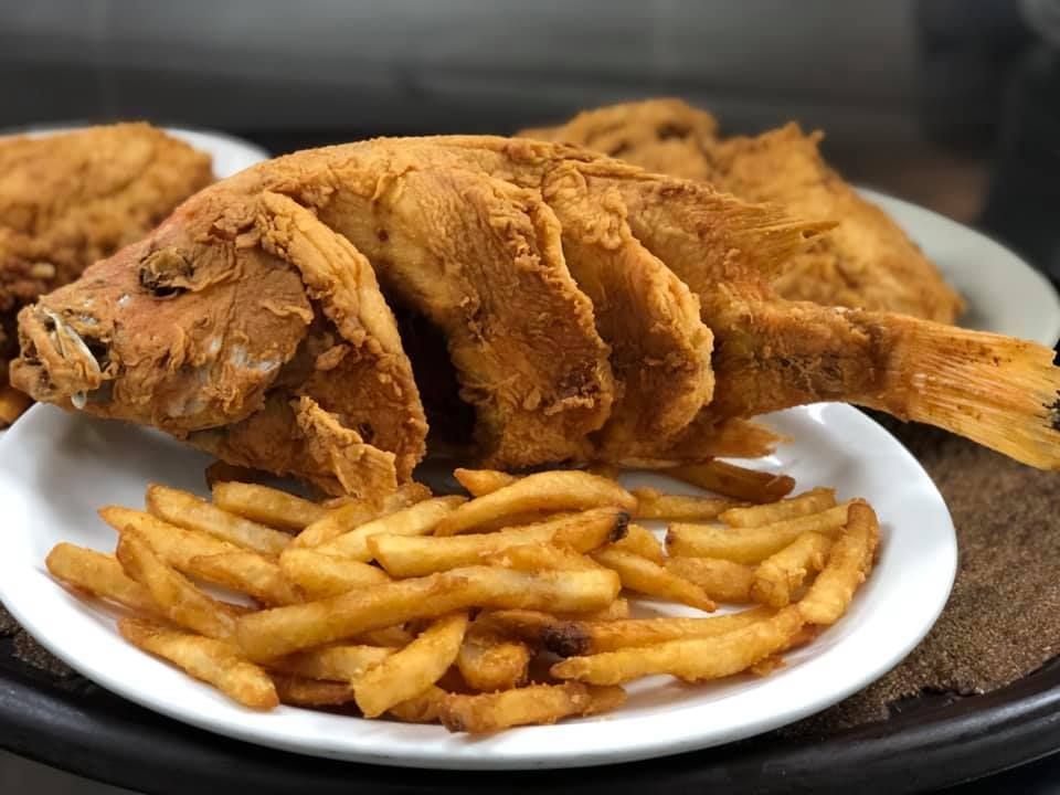 Fried whole fish on a white plate with French fries