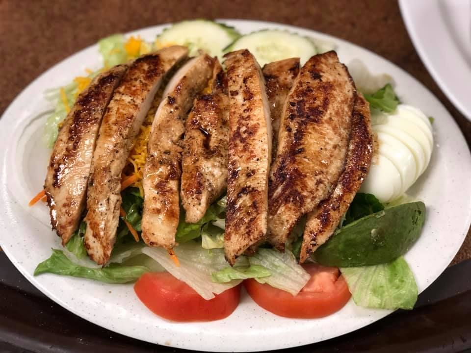 Grilled stuffed flatbread slices on a plate with lettuce, tomato, and cucumber garnish