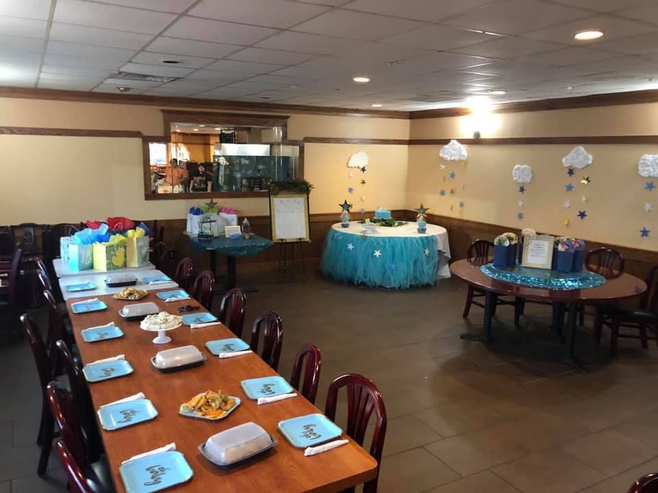 Decorated banquet hall with long tables set for a meal and round tables dressed in blue tablecloths