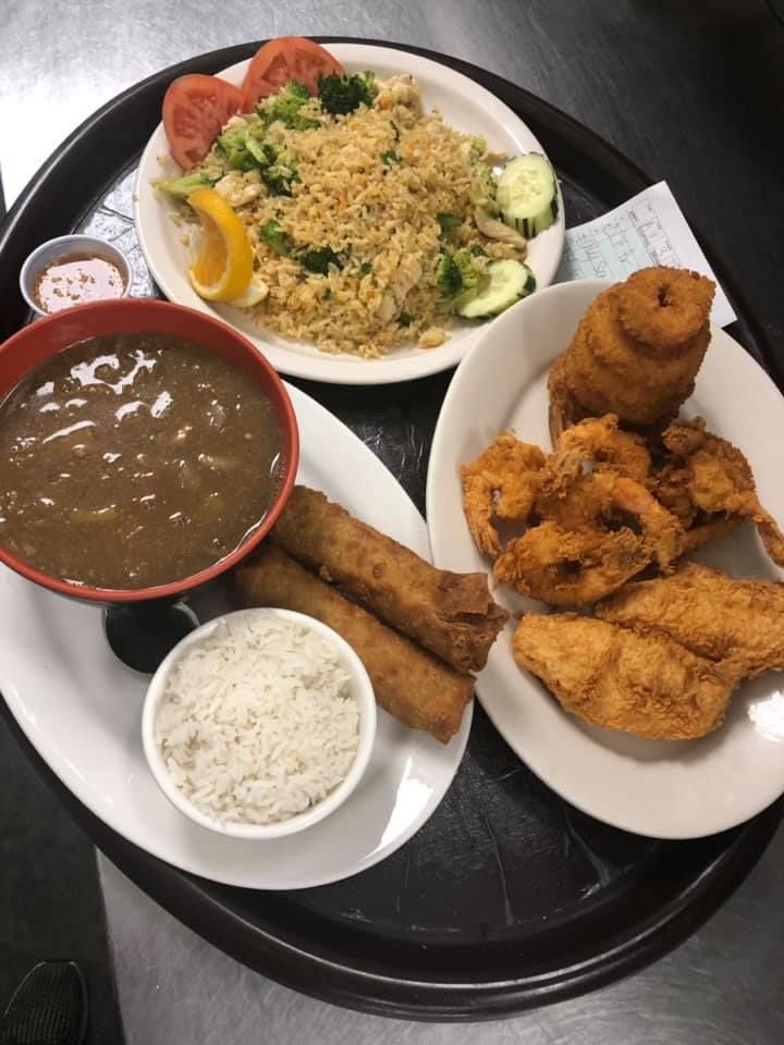 Tray with rice, curry, grilled chicken, fried appetizers, and a salad on black tableware.