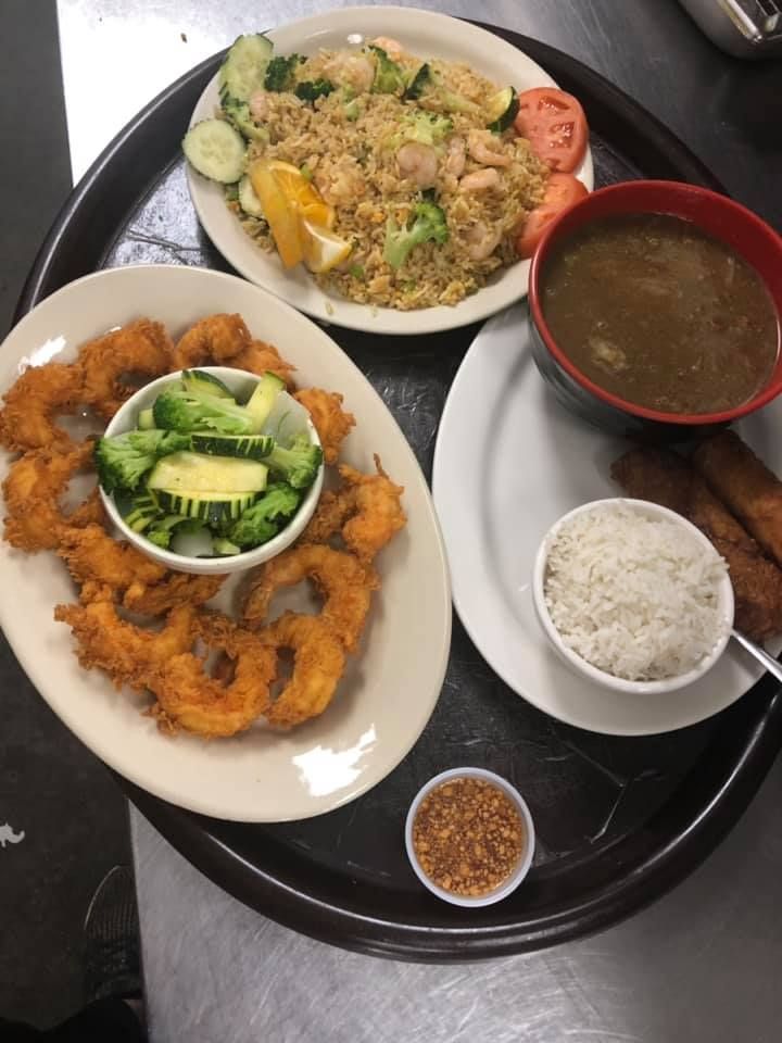 Three Thai dishes on a tray: fried fish, rice with soup, and a noodle salad with vegetables.