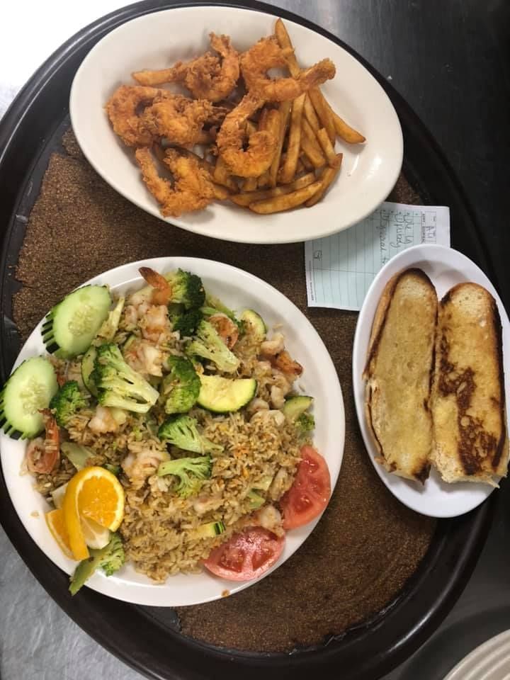 Plated meal with rice, salad, fried shrimp, fries, and garlic bread on a tray