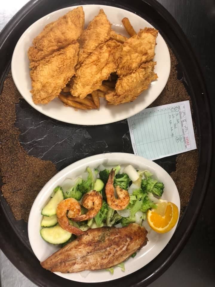 Two plates of fried fish with salad and shrimp on a table, viewed from above