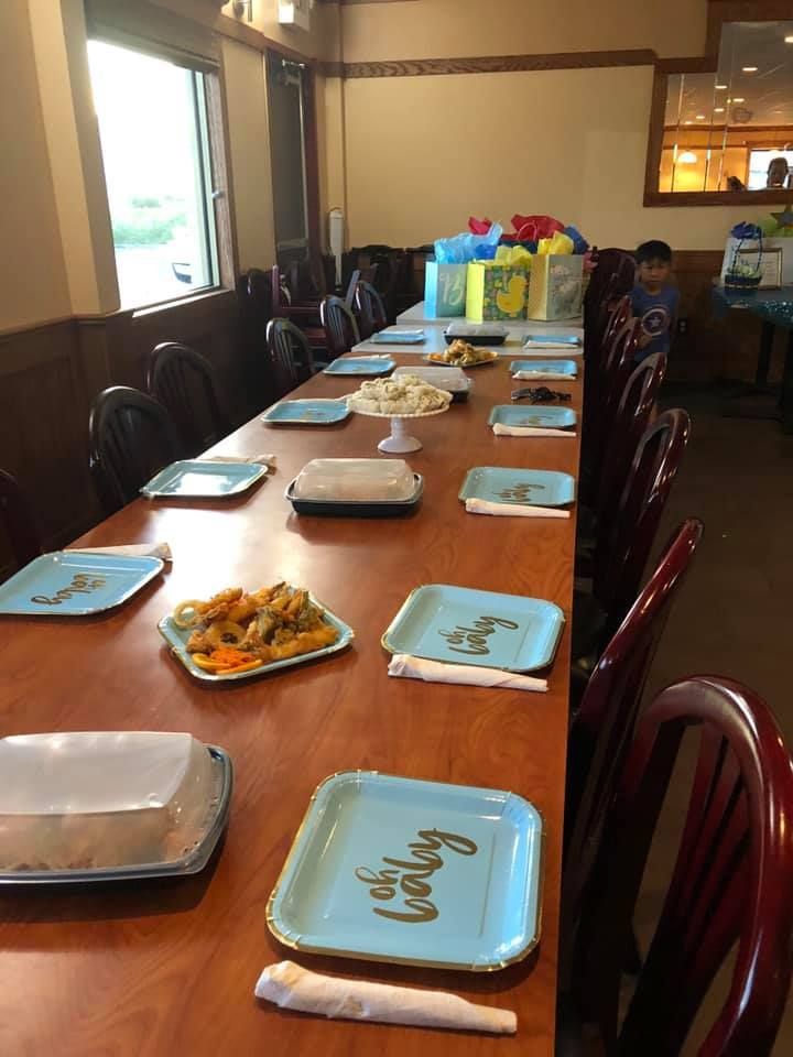 Long dining table set for a meal, with blue plates and trays in a warm indoor room.