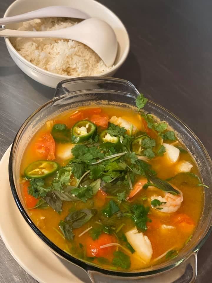 Bowl of vegetable soup with cilantro and jalapeños beside a bowl of rice and spoon