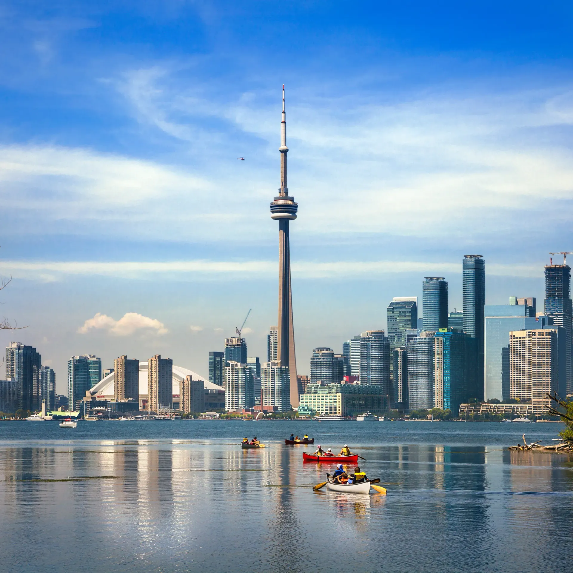 Toronto skyline with CN Tower reflected on calm water and a small boat in the foreground