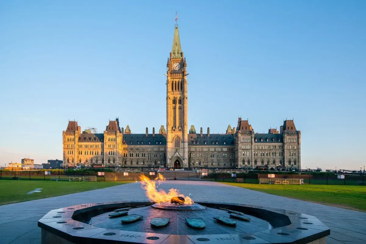 Parliament Buildings at dusk with a lit eternal flame in the foreground