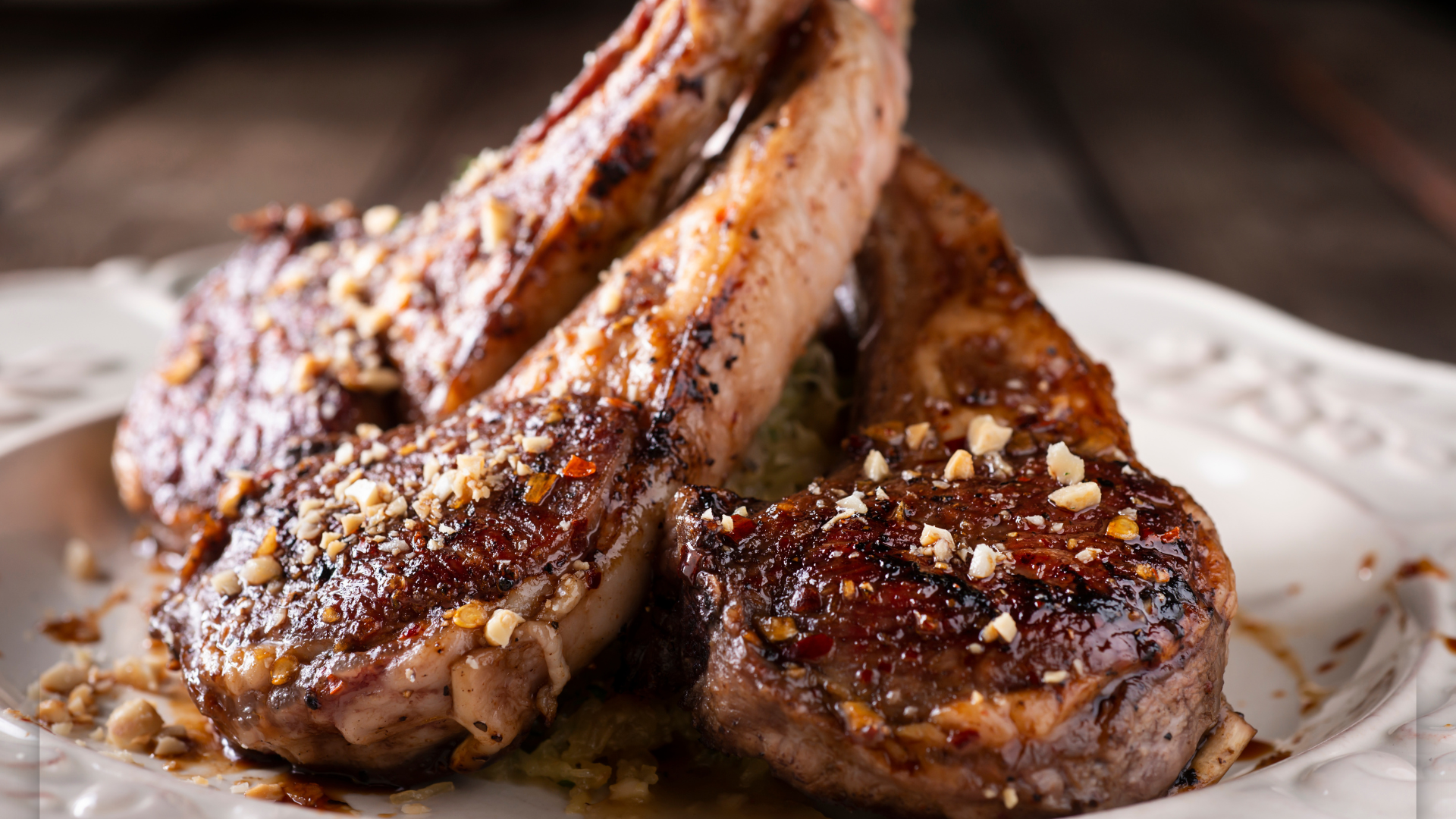 A close up of a plate of lamb chops on a table.
