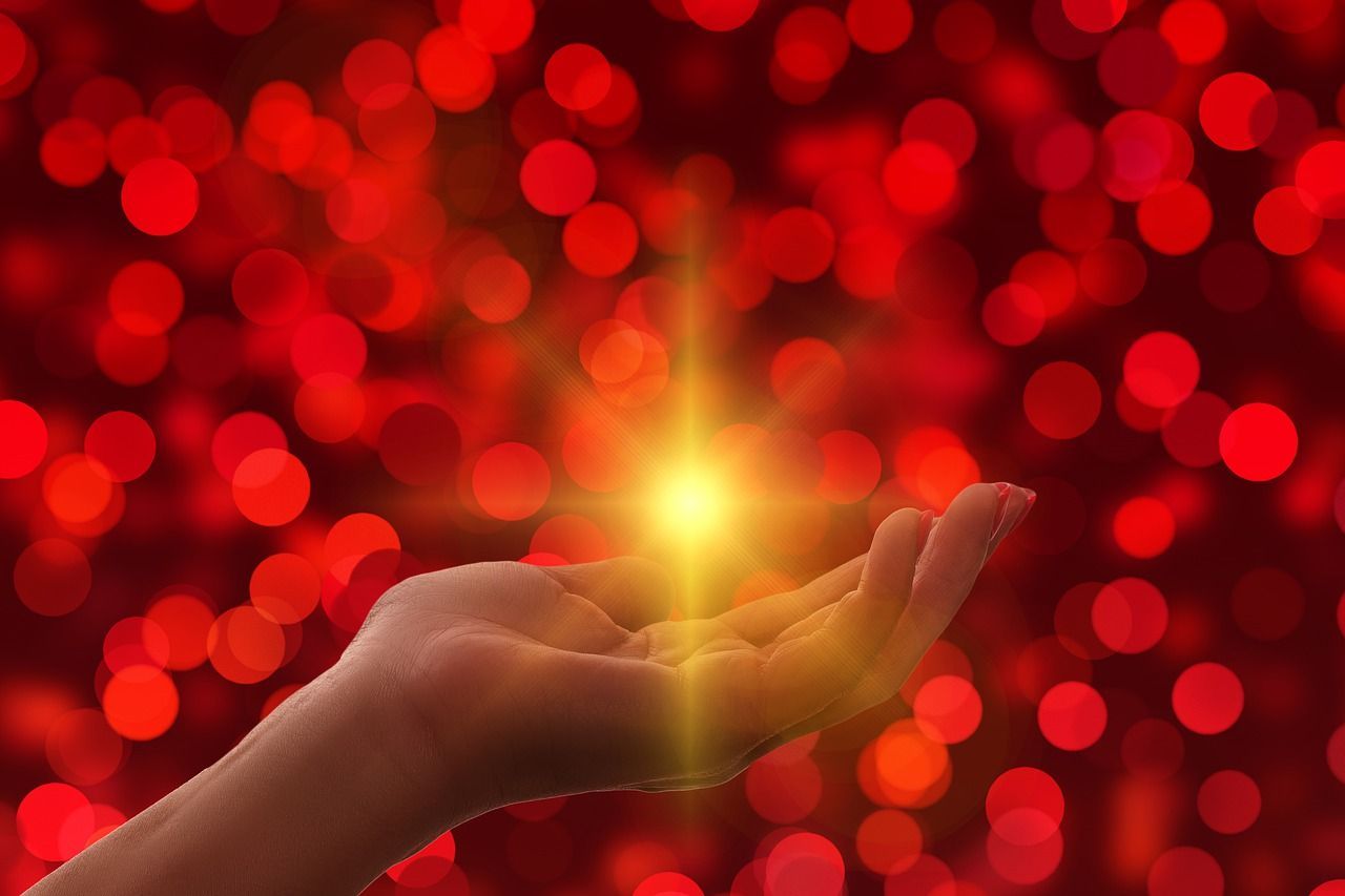 Hands cupping a glowing light against a red bokeh background