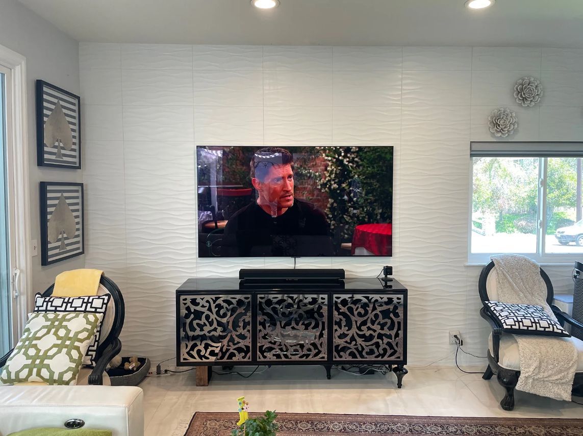Living room with TV on a console, patterned chairs, and bright windows