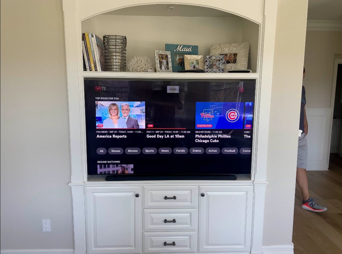 Built-in living room TV cabinet with a flat-screen TV and white storage drawers