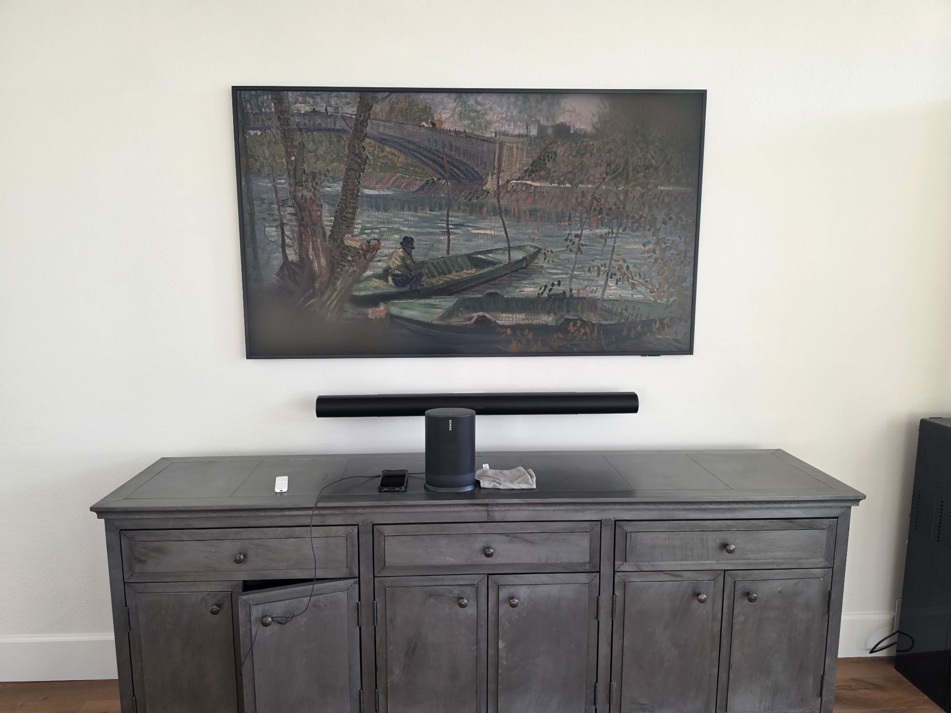 Wall-mounted TV above a gray sideboard with a soundbar and framed art in a living room