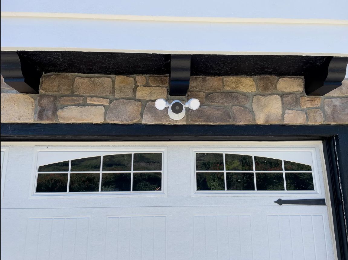 Stone-and-stucco garage facade with a white door and small windows under the eaves