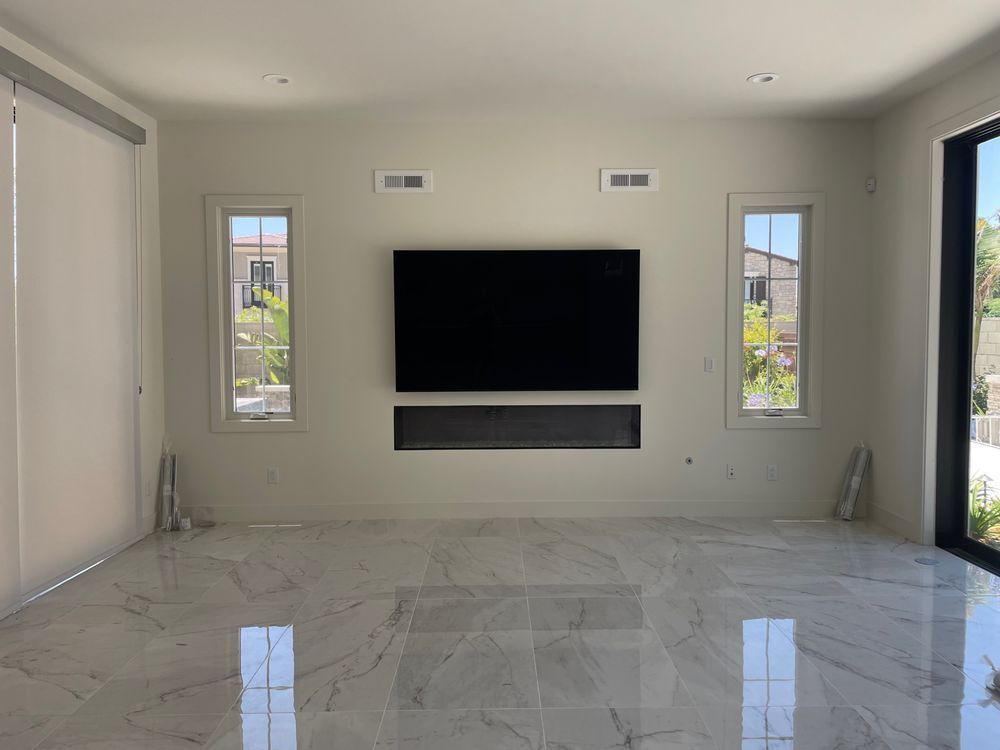 Modern empty living room with marble floor, wall-mounted TV, narrow windows, and a glass door to the right