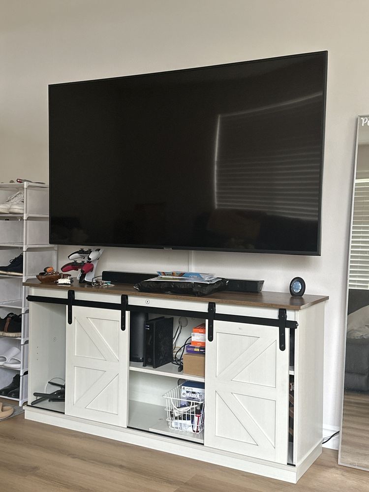 Large flat-screen TV above a white cabinet with open shelves in a living room