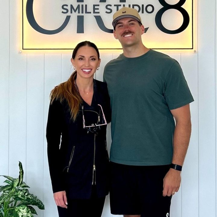 Two people standing and smiling in front of a Smile Studio sign.