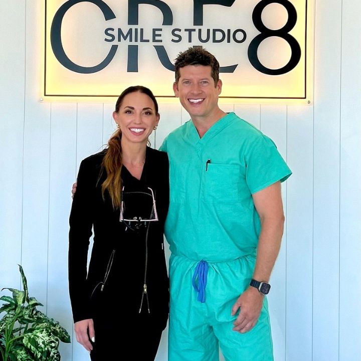 Two people smiling in front of a lit “Smile Studio CR 8” sign
