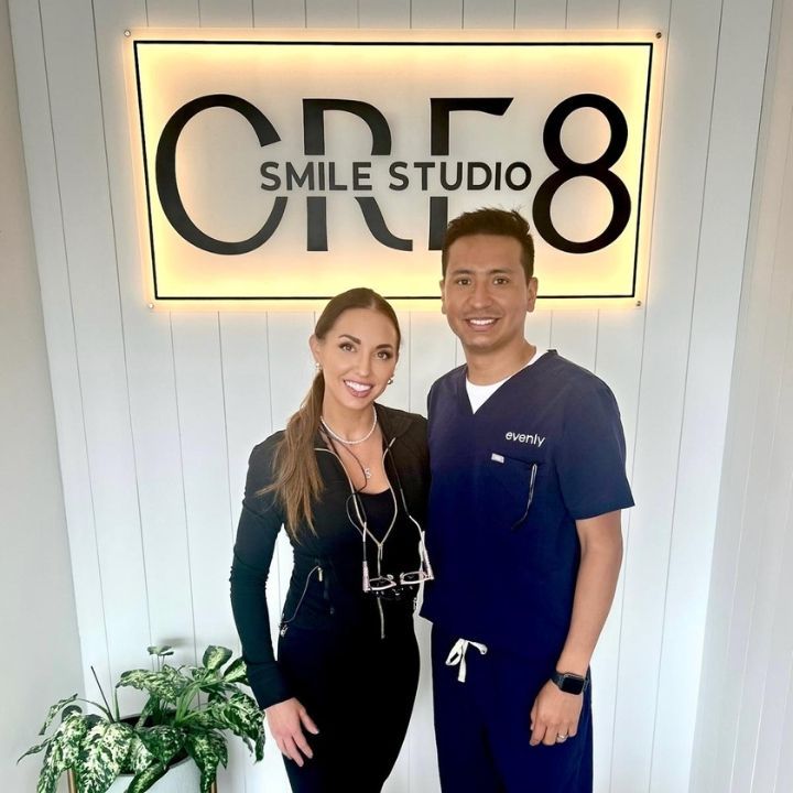 Two people standing indoors under a glowing “Smile Studio 8” sign