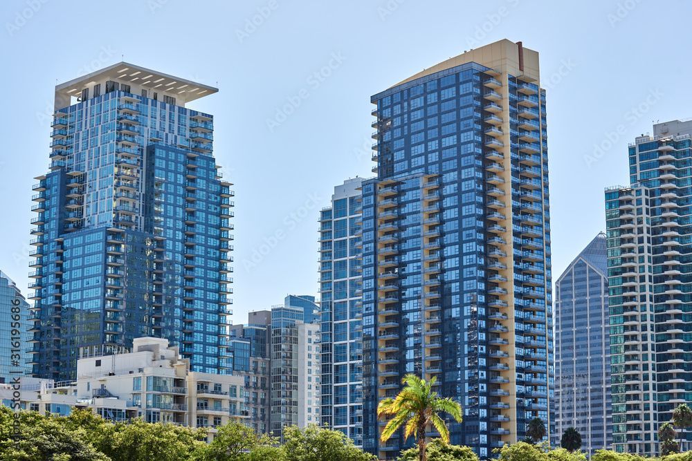 A group of tall buildings in a city with palm trees in the foreground.