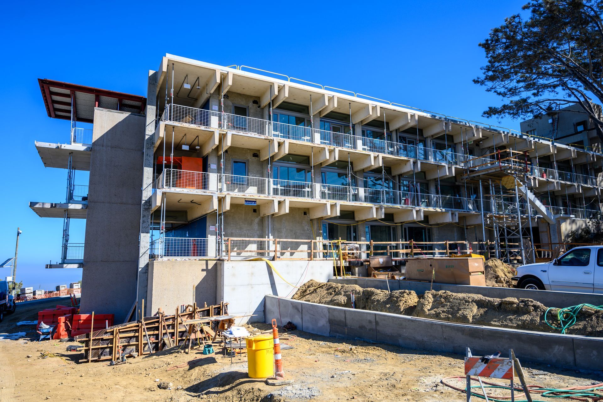 Partially constructed beachfront building with balconies, blue sky, and construction materials in front