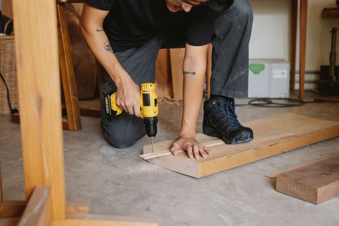 Person kneeling and drilling a wooden board during home renovation