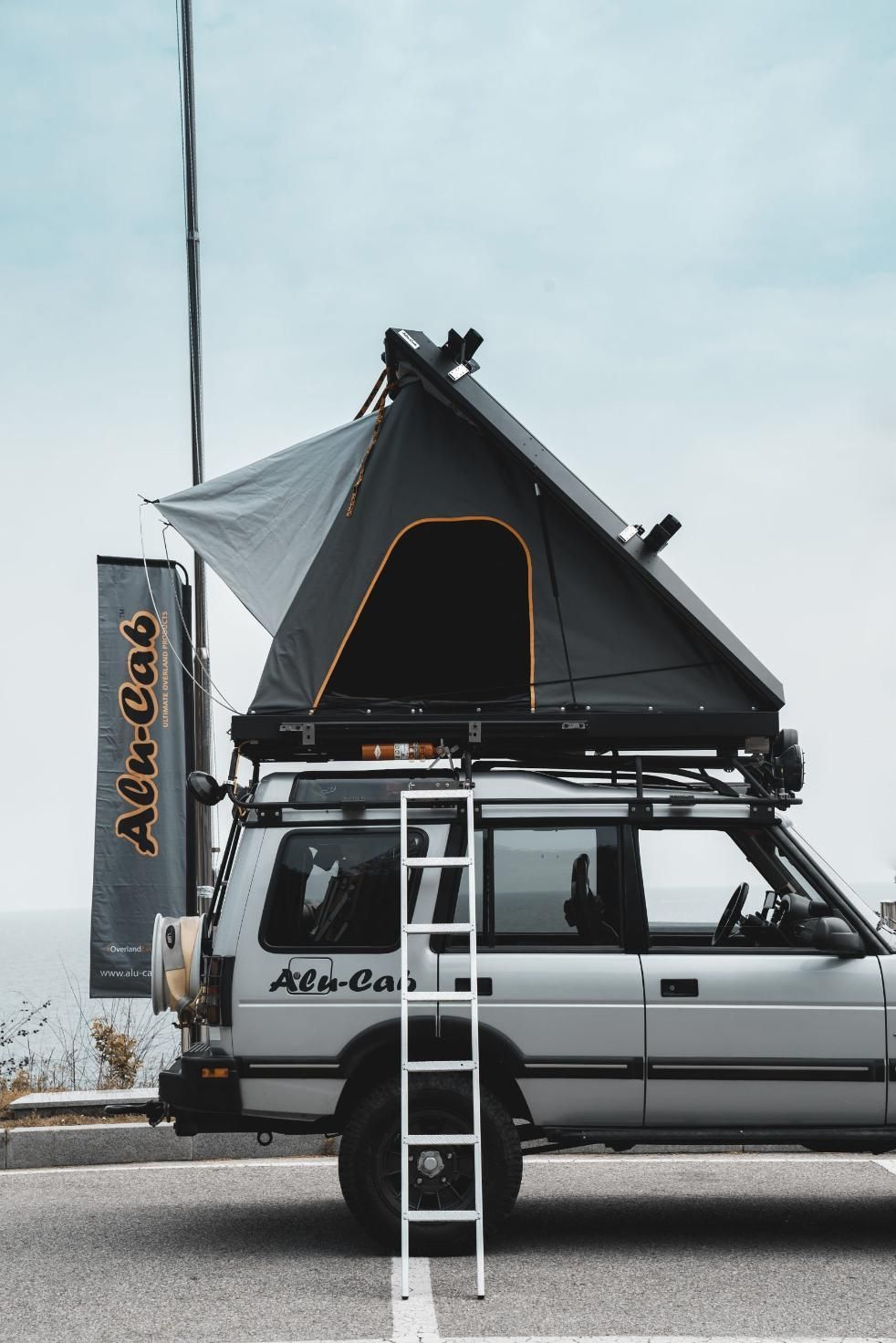 A Car With a Tent on Top of It is Parked on the Side of the Road — Whitsunday 4x4 & Automotive In Cannonvale, QLD